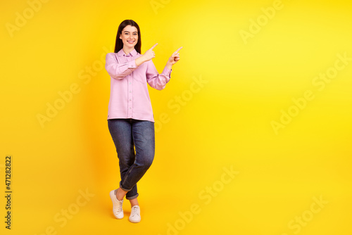 Full size photo of young charming woman indciate fingers empty space promotion isolated over yellow color background