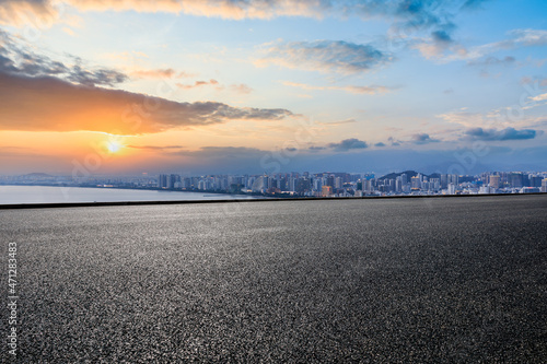 Asphalt road and modern city skyline with buildings at sunrise