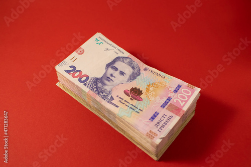 Banknotes in a bundle on a bright red background. Portrait of the writer Lesya Ukrainka on the Ukrainian banknote. Financial concept. photo