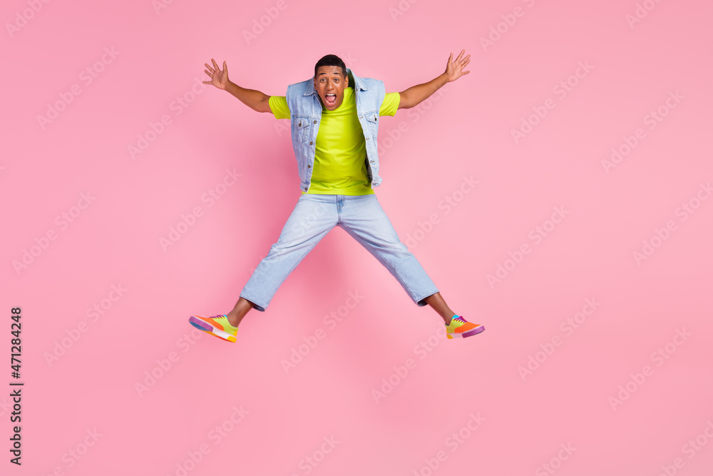 Full length photo of hooray young guy jump wear vest t-shirt jeans sneakers isolated on pink background Full length photo of hooray young guy jump wear vest t-shirt jeans sneakers isolated on pink background