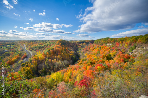 Beautiful Autumn colours views of the Spencer Gorge along the Dundas Peak trail in Hamilton, Ontario, Canada. Train tracks are visible from the lookout. Clouds are present on the blue sky. photo