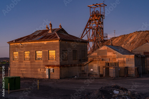 Abandoned sheds and poppet head at a mining plant at twilight