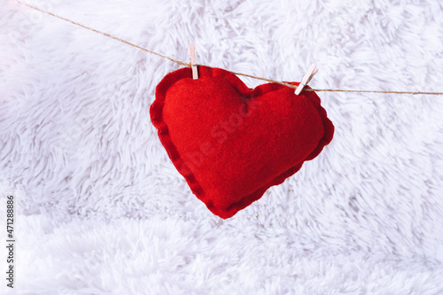 Minimal concept. The red heart is drying on a string with white snowy background. Creative New Year, Christmas or Valentins idea.