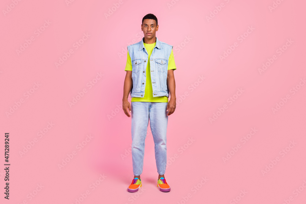 Full size photo of nice young brunet guy wear t-shirt vest jeans sneakers isolated over pink color background Full size photo of nice young brunet guy wear t-shirt vest jeans sneakers isolated over pink color background