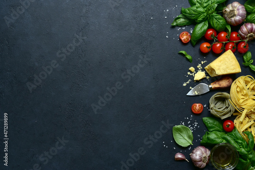 Culinary background with traditional ingredients of italian cuisine : pasta, tomatoes, garlic, olive oil, parmesan cheese, basil. Top view with copy space.