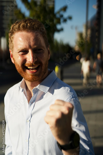 Young happy businessman outdoors. Portrait of handsome man talking to the phone. © JustLife