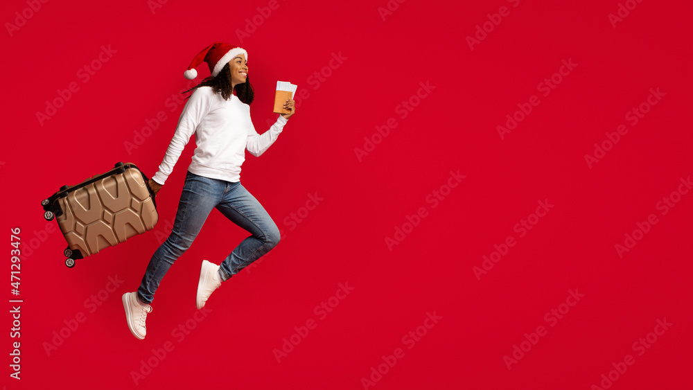 Emotional black woman in Santa hat holding suitcase and passport Emotional black woman in Santa hat holding suitcase and passport