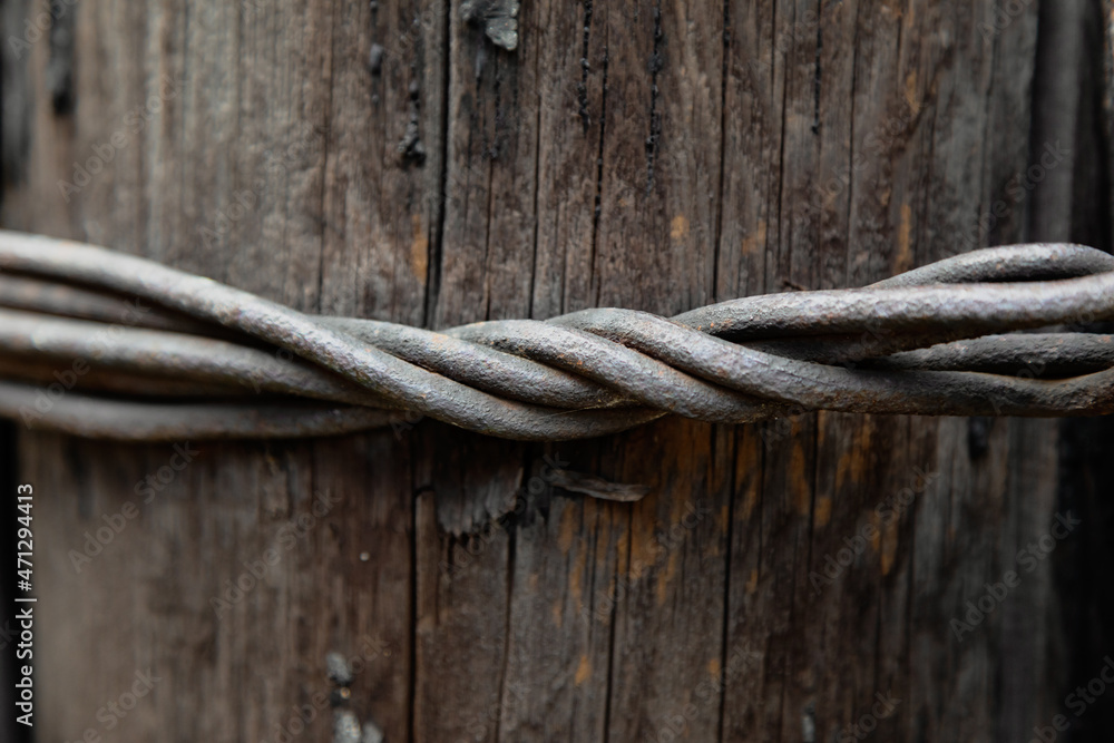 Obraz premium Old twisted wire on a wooden background. Thick rusty wire twisted around a pillar.