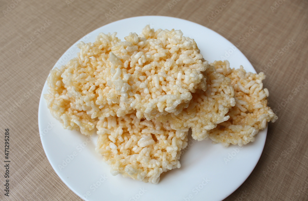 Rengginang, traditional crackers from Indonesia, made from sticky rice which dried then fried. On a white plate. Rengginang, traditional crackers from Indonesia, made from sticky rice which dried then fried. On a white plate.