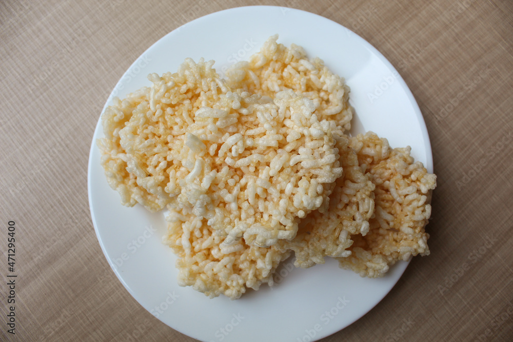 Rengginang, traditional crackers from Indonesia, made from sticky rice which dried then fried. On a white plate. Rengginang, traditional crackers from Indonesia, made from sticky rice which dried then fried. On a white plate.