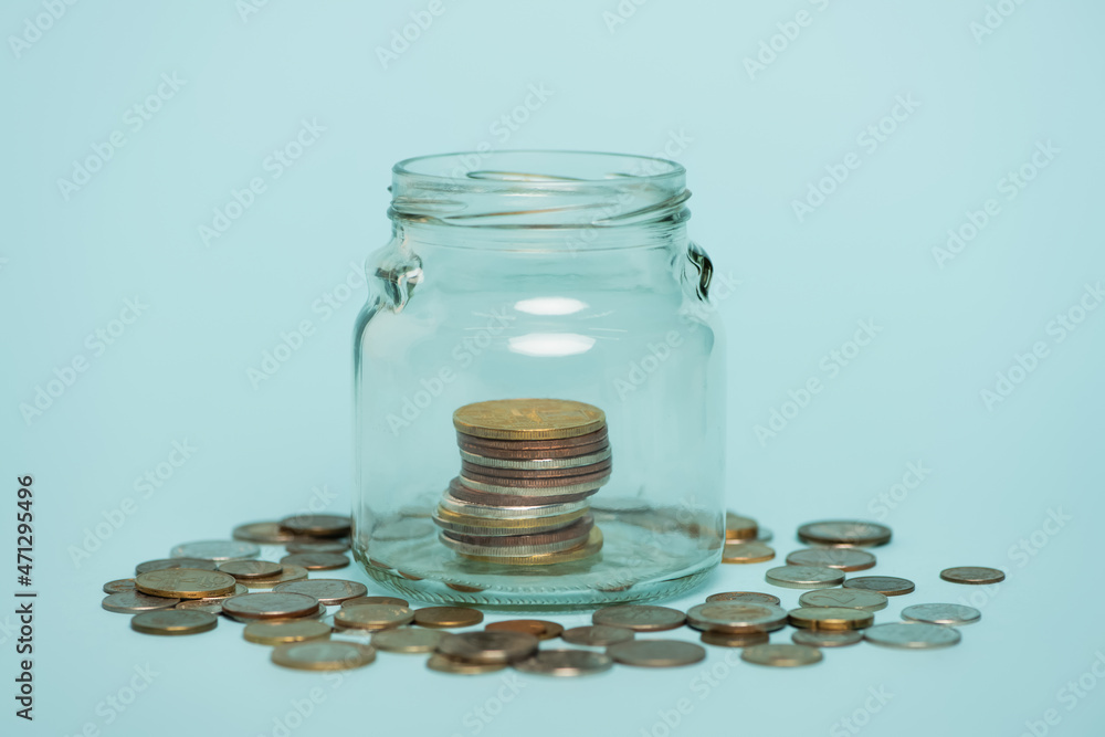 glass jar with money near scattered coins on blue background, anti-corruption concept glass jar with money near scattered coins on blue background, anti-corruption concept