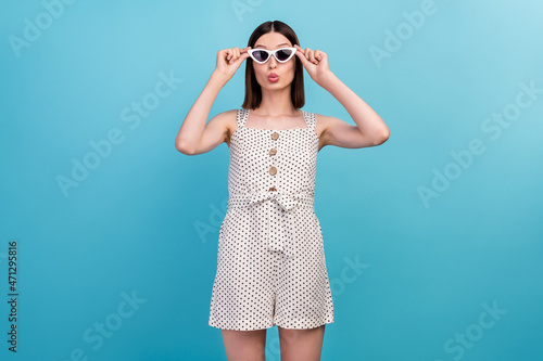 Photo of romantic tourist tempting lady blow air kiss wear sunglass dotted overall isolated blue color background