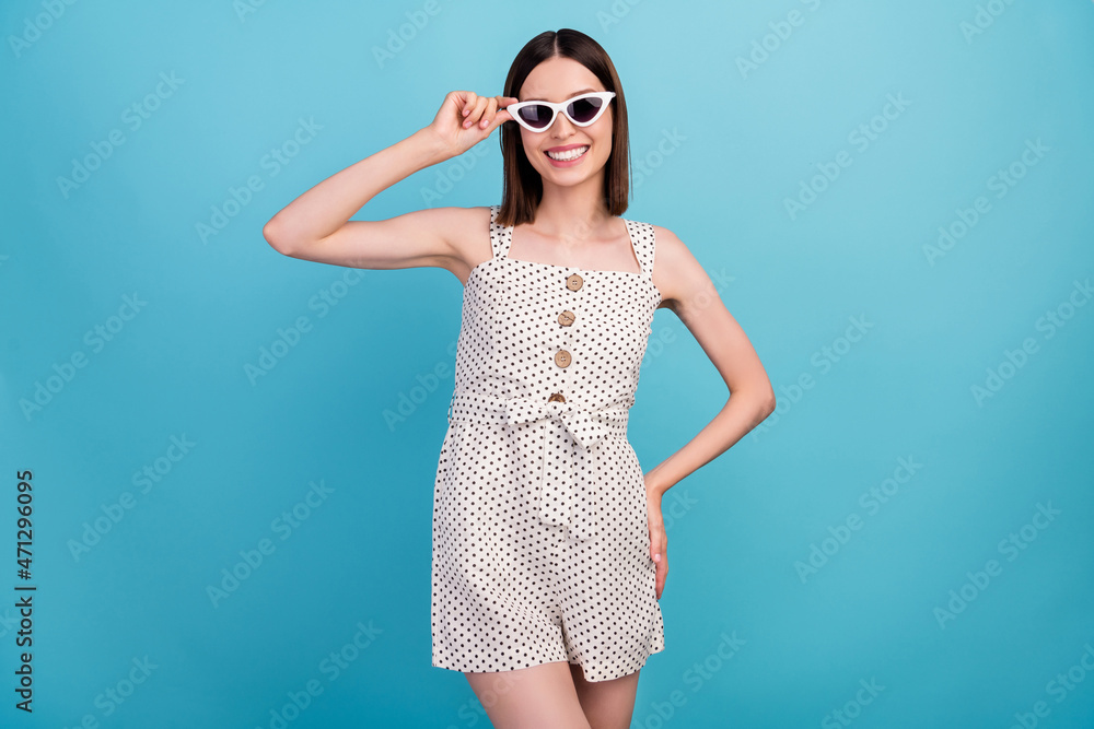 Photo of lovely pretty lady summer weekend hand hip wear sunglass dotted overall isolated blue color background Photo of lovely pretty lady summer weekend hand hip wear sunglass dotted overall isolated blue color background