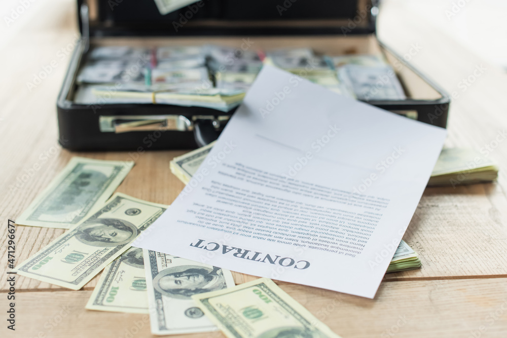 Obraz premium contract near dollar banknotes and blurred briefcase with money, anti-corruption concept