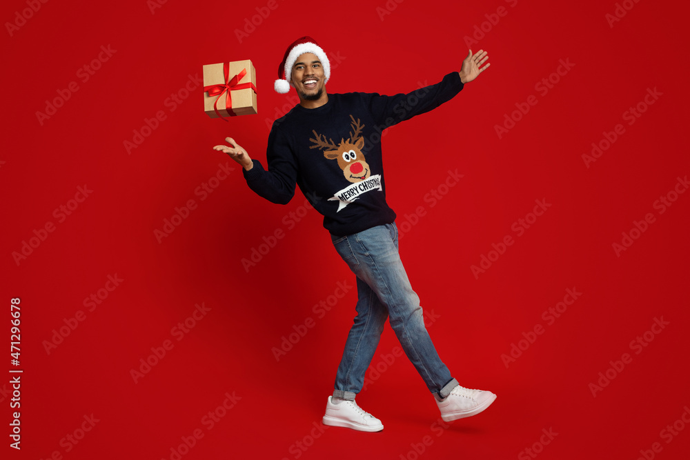 Handsome black guy in Santa hat playing with xmas gift