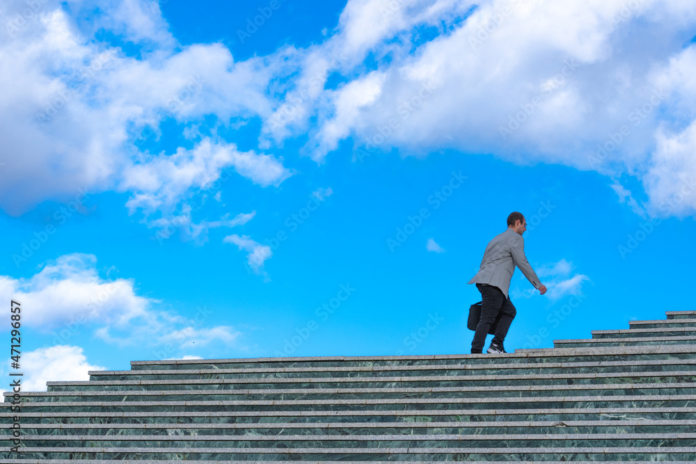 Caucasian businessman going upstairs with blue sky in the background Caucasian businessman going upstairs with blue sky in the background