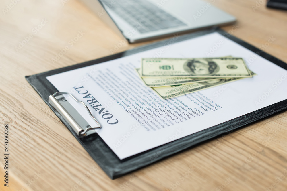 Obraz premium dollar banknotes on contract near blurred laptop, anti-corruption concept