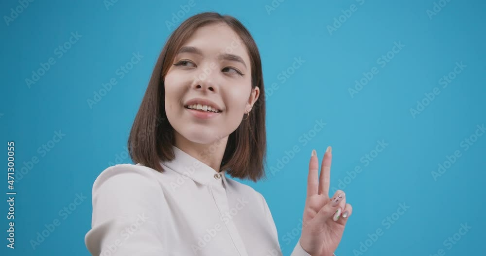 Young beautiful teenage girl makes a selfie on a blue background. Close-up. Young beautiful teenage girl makes a selfie on a blue background. Close-up.