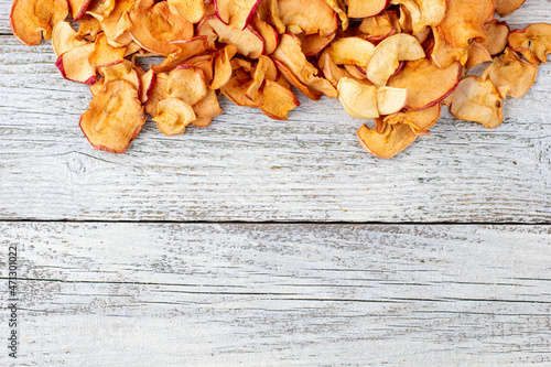 A pile of dried apples in slices on a white wooden background. Dried fruit chips. Healthy food
