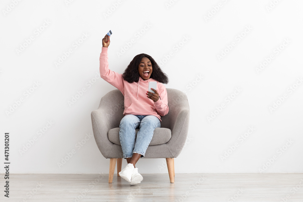 Emotional african american woman holding credit card and cellphone Emotional african american woman holding credit card and cellphone