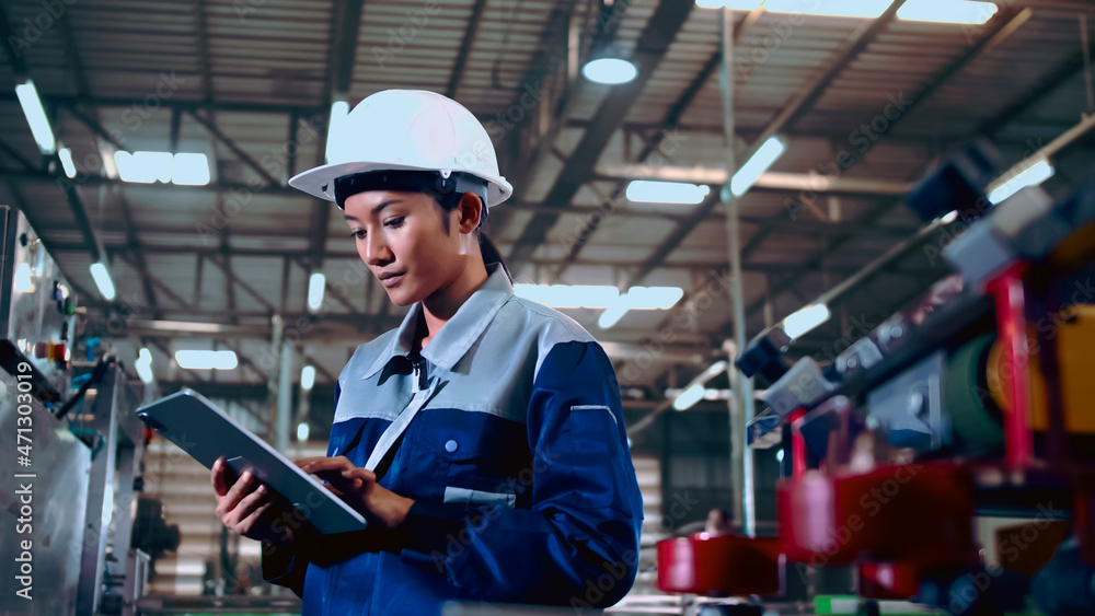 Fototapeta premium Engineer is using a tablet to check the machine's control system in a factory.