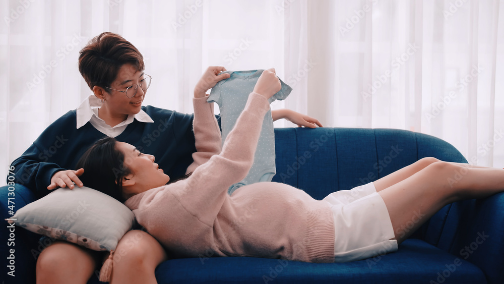 Pregnant Asian lesbian woman and her partner are happy to spend time together at home. Pregnant Asian lesbian woman and her partner are happy to spend time together at home.