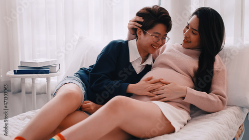 Pregnant Asian lesbian woman and her partner are happy to spend time together at home.