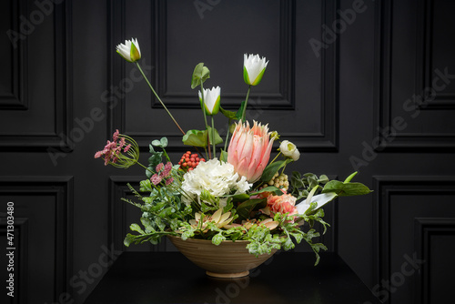 Plastic handmade bouquet artificial flowers composition.Beautiful flowers in vase on a table with black  background. Women's, mother's day. Spring, summer season. Front view.Selective focus.
