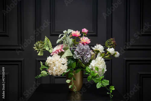 Plastic handmade bouquet artificial flowers composition.Beautiful flowers in vase on a table with black  background. Women's, mother's day. Spring, summer season. Front view.Selective focus.
