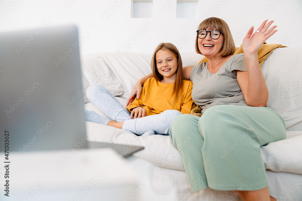 White girl and her grandmother gesturing while using laptop on sofa White girl and her grandmother gesturing while using laptop on sofa