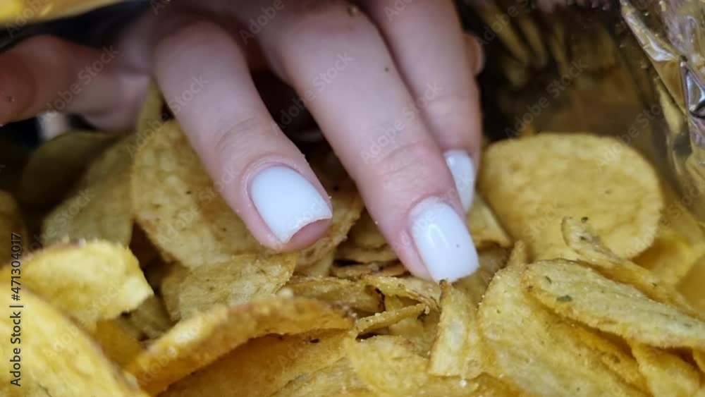 The hand takes out chips from the package, inside view The hand takes out chips from the package, inside view