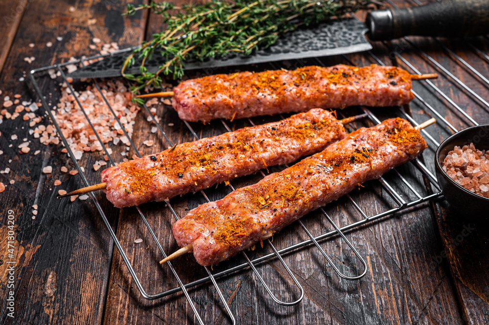 Uncooked Raw Urfa shish kebab on a grill with pink salt. Wooden background. top view