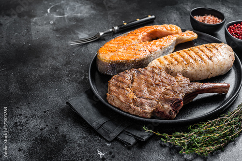 Grilled meat steaks - fish salmon, beef veal and turkey fillet. Black background. Top view. Copy space