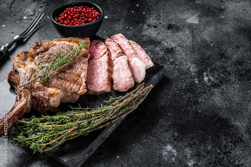 Grilled Tomahawk Beef Steak, Rib eye with thyme. Black background. Top view. Copy space