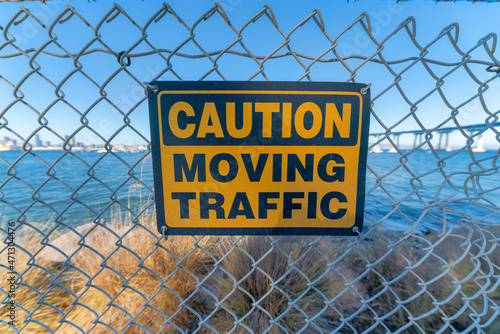 Caution moving traffic sign on a mesh wire fence at Coronado, San Diego, California