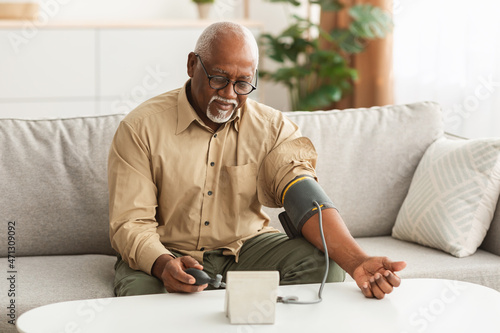 Senior African American Man Measuring Arterial Blood Pressure At Home photo