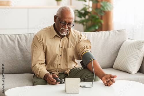 Foto Senior African American Man Measuring Arterial Blood Pressure At Home
