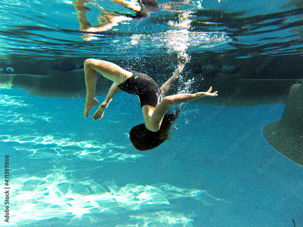Young girl swimming underwater at a pool Stock Photo | Adobe Stock