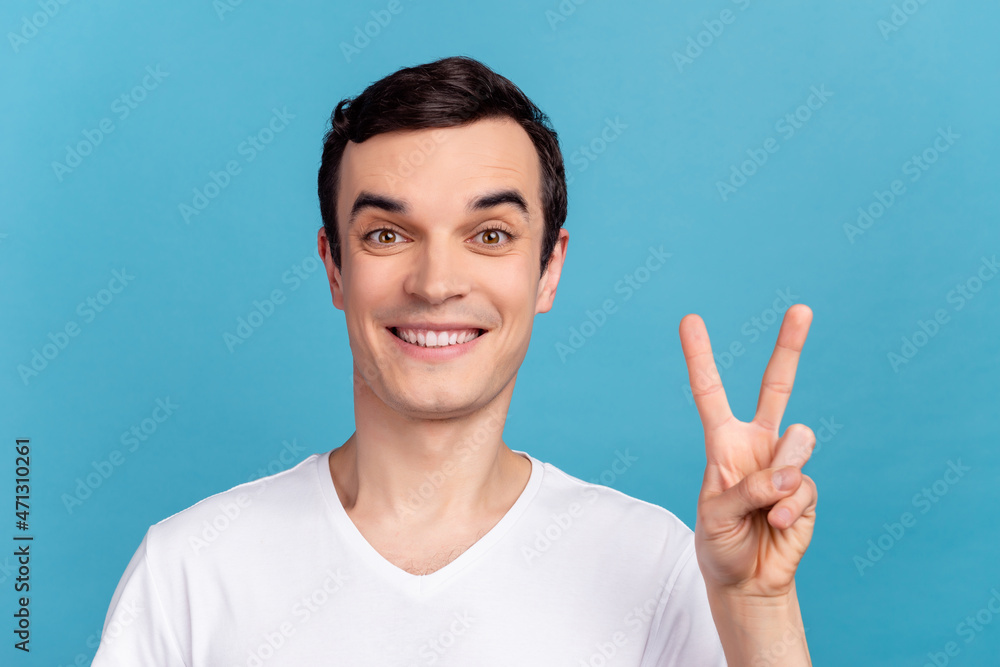 Photo of young cheerful guy show fingers peace cool v-symbol casual outfit isolated over blue color background Photo of young cheerful guy show fingers peace cool v-symbol casual outfit isolated over blue color background