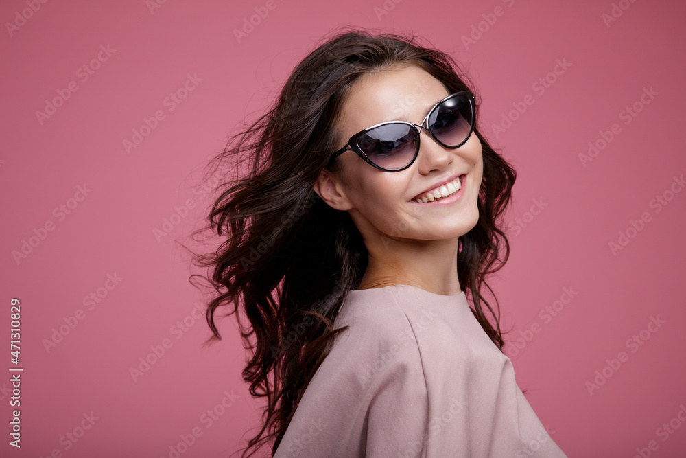 High fashion photo of a beautiful elegant young woman in a pretty pink jumpsuit, sunglasses posing on pink background. Slim figure. Studio Shot. Luxurious hair, shiny curls. Femininity and tenderness High fashion photo of a beautiful elegant young woman in a pretty pink jumpsuit, sunglasses posing on pink background. Slim figure. Studio Shot. Luxurious hair, shiny curls. Femininity and tenderness