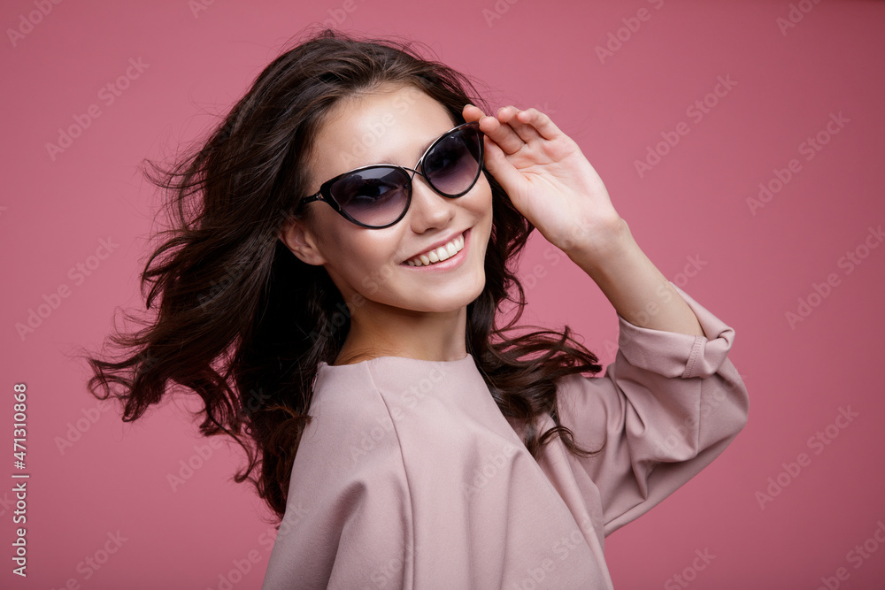High fashion photo of a beautiful elegant young woman in a pretty pink jumpsuit, sunglasses posing on pink background. Slim figure. Studio Shot. Luxurious hair, shiny curls. Femininity and tenderness High fashion photo of a beautiful elegant young woman in a pretty pink jumpsuit, sunglasses posing on pink background. Slim figure. Studio Shot. Luxurious hair, shiny curls. Femininity and tenderness