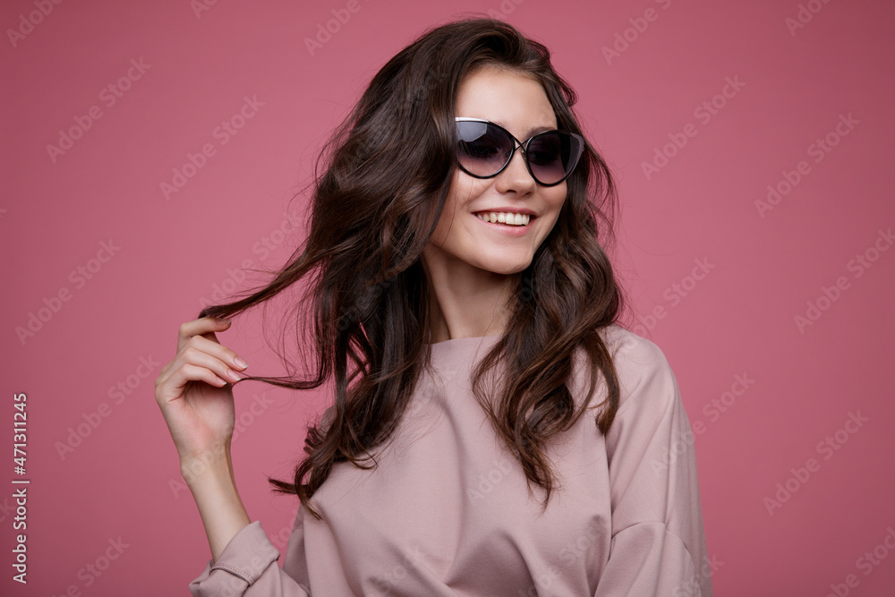 High fashion photo of a beautiful elegant young woman in a pretty pink jumpsuit, sunglasses posing on pink background. Slim figure. Studio Shot. Luxurious hair, shiny curls. Femininity and tenderness High fashion photo of a beautiful elegant young woman in a pretty pink jumpsuit, sunglasses posing on pink background. Slim figure. Studio Shot. Luxurious hair, shiny curls. Femininity and tenderness
