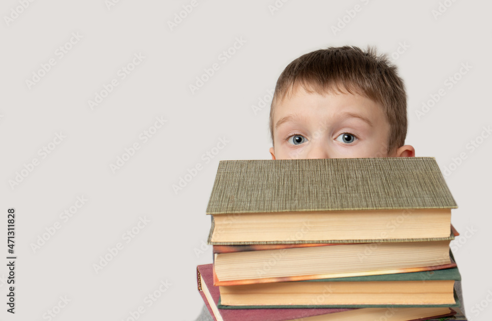 Little preschooler boy hiding behind a big stack of books. Education concept, fiction Little preschooler boy hiding behind a big stack of books. Education concept, fiction