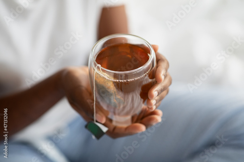 Unrecognizable black woman in pajams holding mug with tea photo