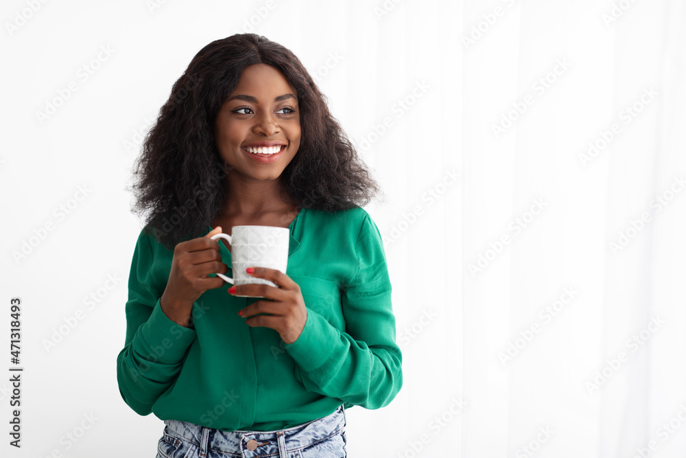 Cheerful attractive black lady posing at home, drinking coffee Cheerful attractive black lady posing at home, drinking coffee