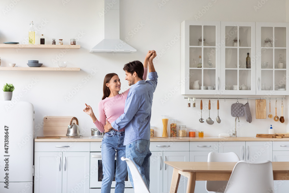 Cheerful millennial european husband and wife have fun and dancing in modern kitchen interior Cheerful millennial european husband and wife have fun and dancing in modern kitchen interior
