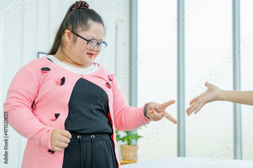 Girls playing rock-paper-scissors with Asian family at home smiling and having fun. The concept is a girl with Down syndrome with her mother.