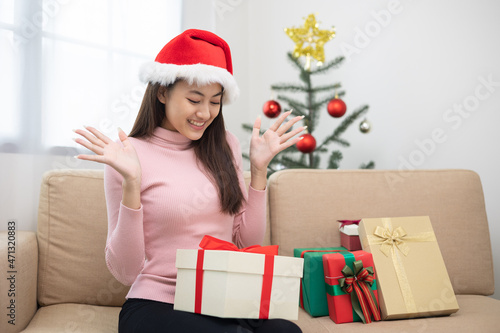 Beautiful Asian woman feeling happy and excited celebrate with present gift box in christmas party. Cute girl in christmas holiday with gift box sitting in living room. Happy new year festival.