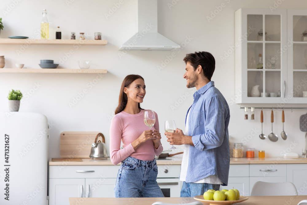Smiling millennial caucasian family with glasses of wine in modern kitchen interior, celebrate anniversary Smiling millennial caucasian family with glasses of wine in modern kitchen interior, celebrate anniversary