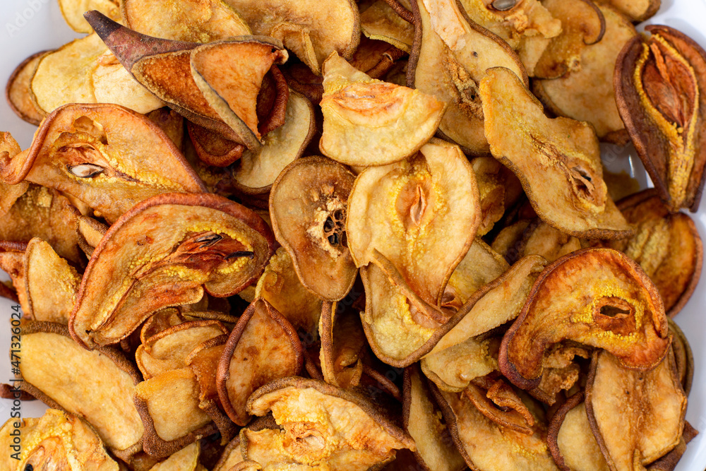 A pile of dried pears in slices on a white plate on wooden background. Dried fruit chips. Healthy food A pile of dried pears in slices on a white plate on wooden background. Dried fruit chips. Healthy food